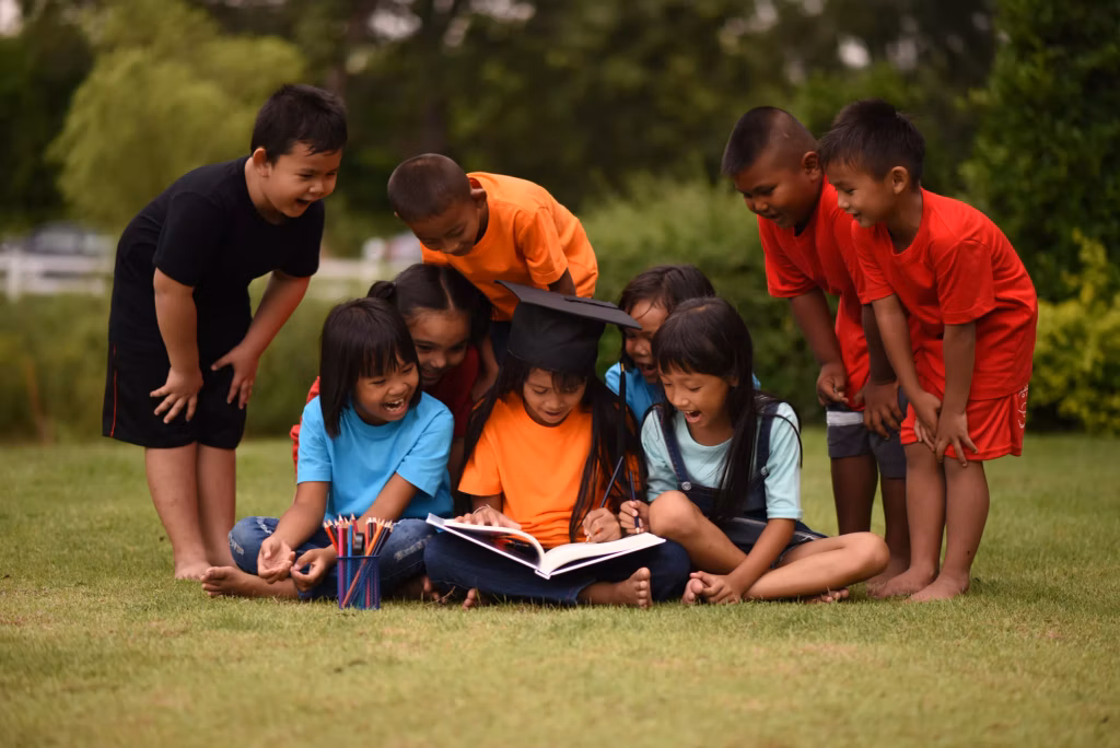 Group of children lying reading on grass field - Bali Dive Resort