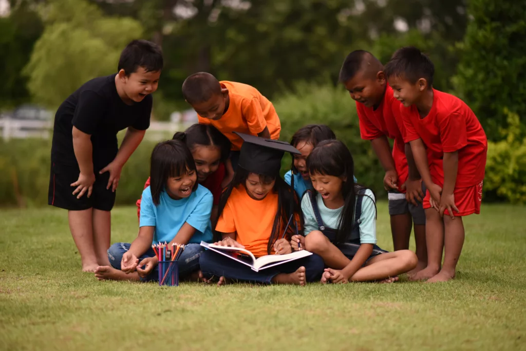 Group of children lying reading on grass field - Bali Dive Resort