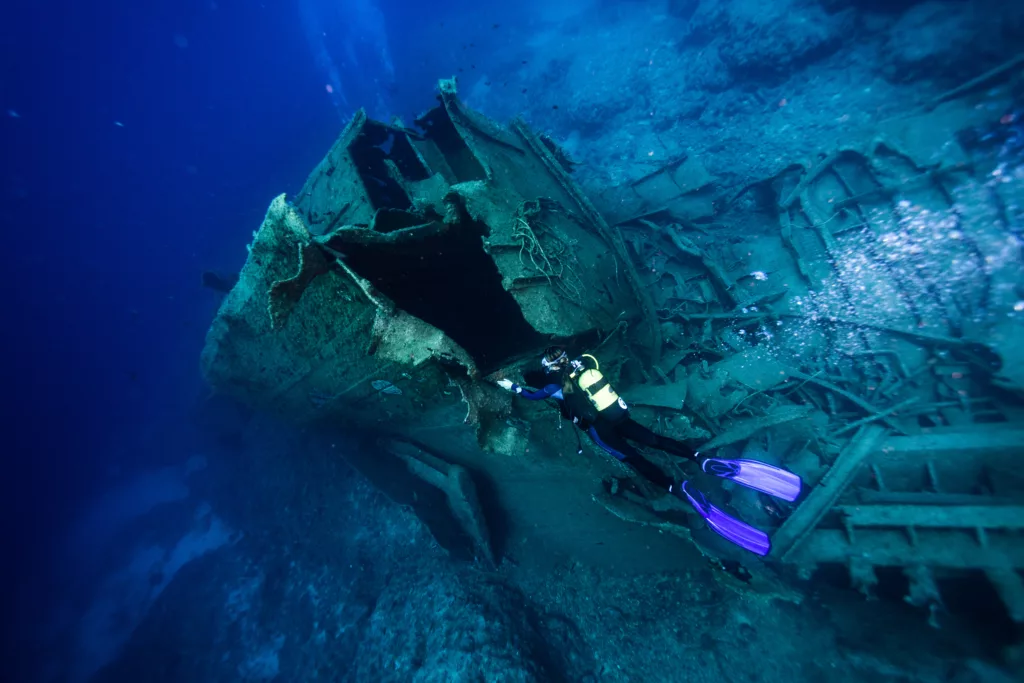 scuba diver swimming by obsolete ship undersea - Boga Wreck