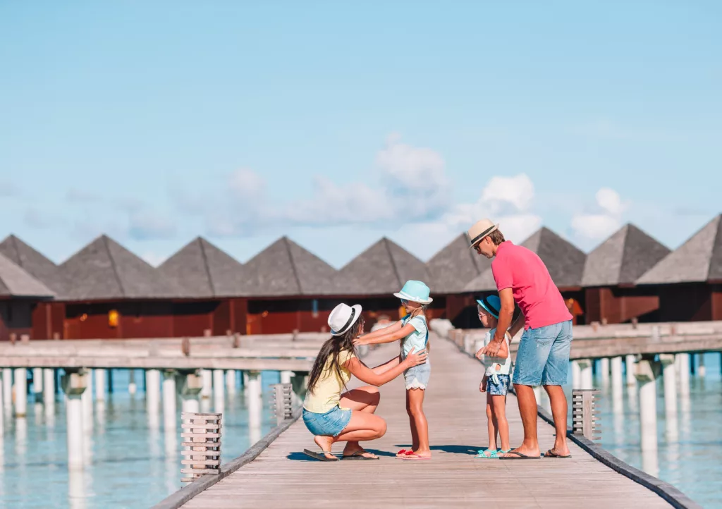 Happy family of four on a beach during summer vacation - Bali dive resort