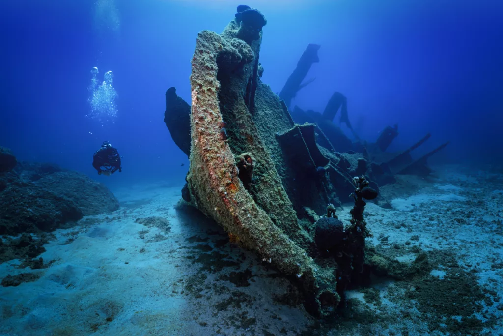 A scuba diver explores a sunken shipwreck at the Boga Wreck - magic dive sites