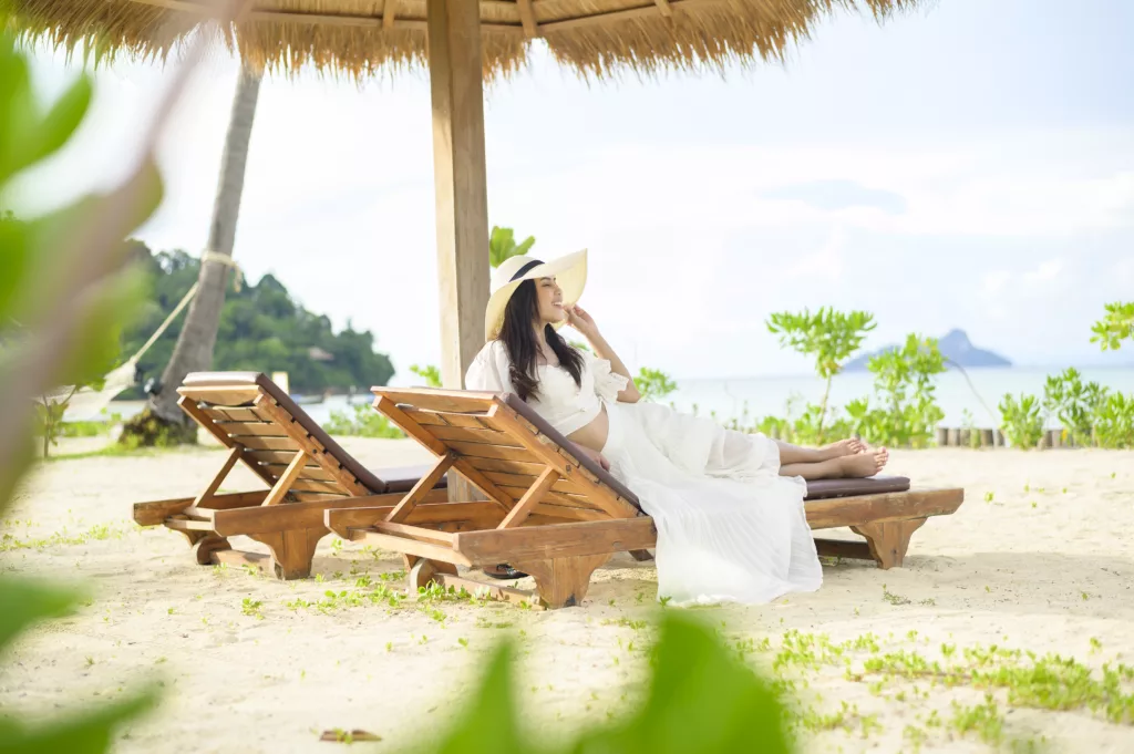 A young woman relaxing and sitting on the lounge chair looking at beautiful beach on holidays - Bali dive resort